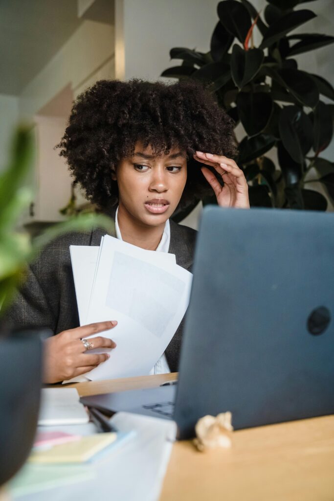 Focused woman feeling stressed while working with laptop and documents at her desk.